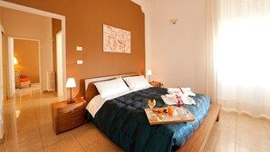 A neatly arranged bedroom with a bed, bedside tables, a tray of breakfast items, and a painting on the wall. - Fourseasons (Lecce)