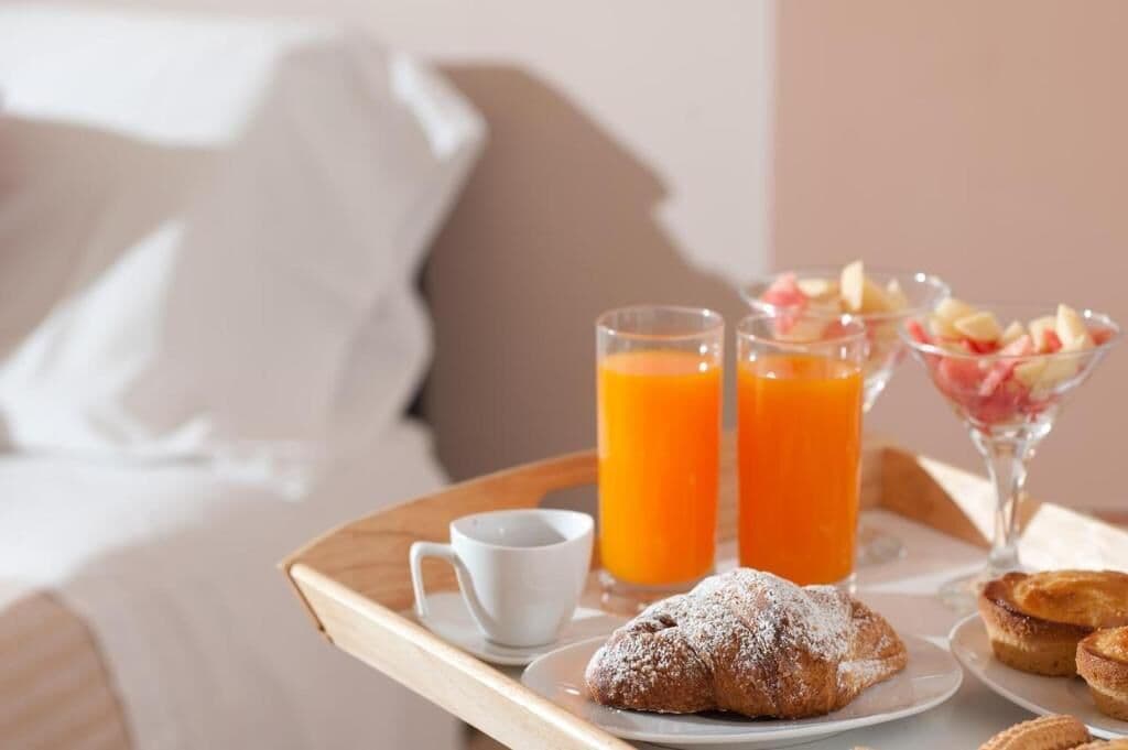 A breakfast tray with pastries, a cup of coffee, and two glasses of orange juice on a wooden table.