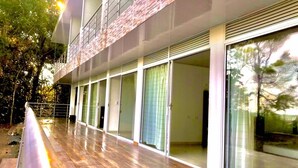 Un edificio moderno con terraza de madera, grandes puertas correderas de vidrio y un balcón.