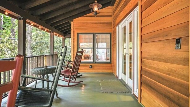 Un porche de madera con mecedoras, techo de madera y vistas al exterior.