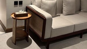 Una sala de estar moderna con un sofá beige, una mesita de madera y un aplique de pared.