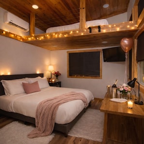 Une chambre à coucher avec un lit, une table de chevet, une lampe et une fenêtre donnant sur un beau paysage.