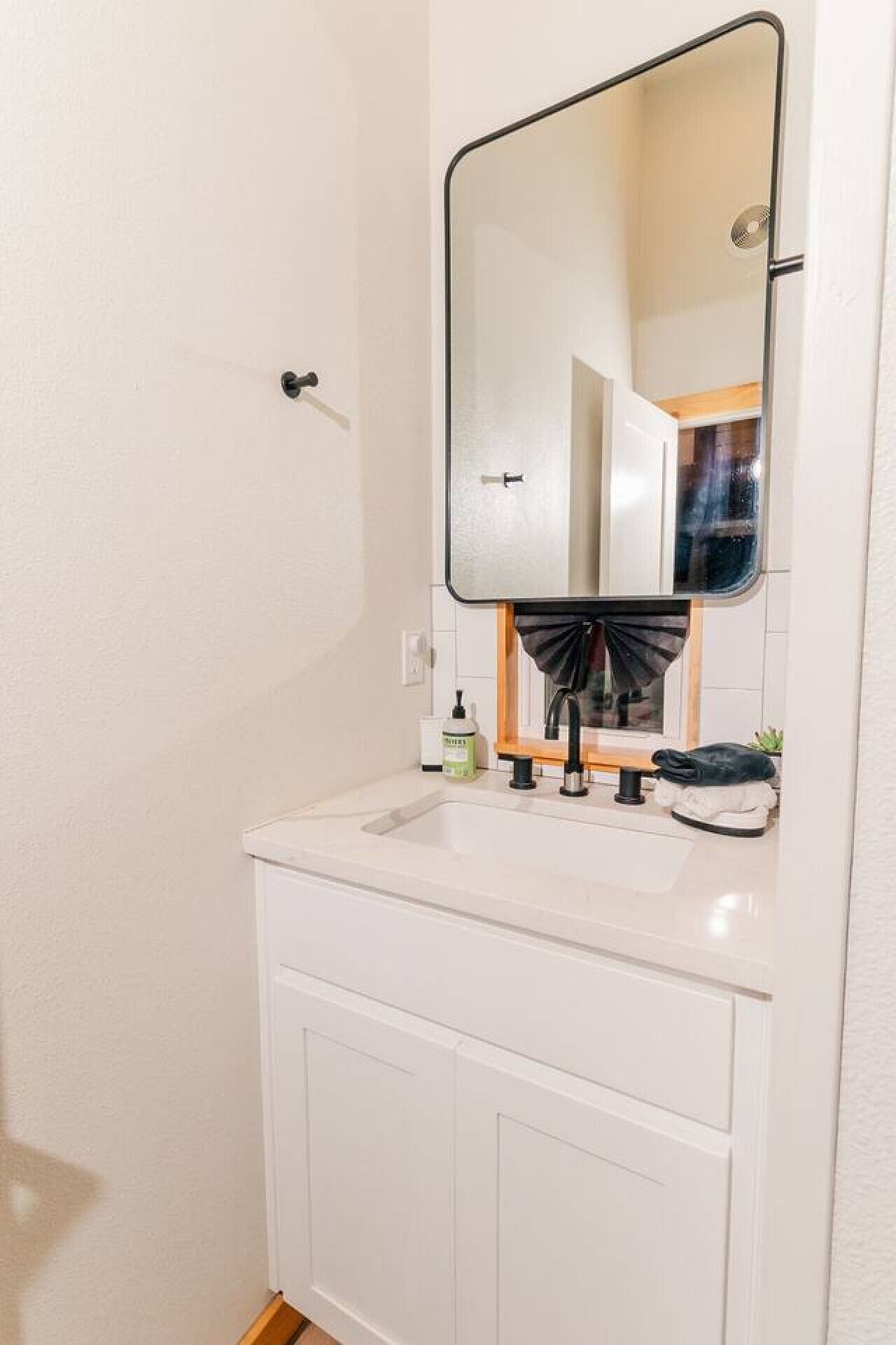 A small, white bathroom with a single sink, a mirror, and a door.