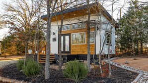 A modern cabin with a wooden exterior, large windows, and a small porch area.