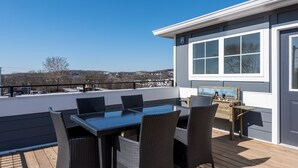 A deck with a table and chairs, a wooden bench, and a view of the surrounding area.