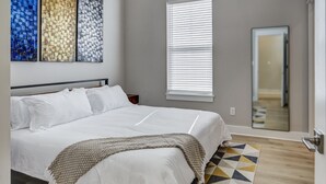A bedroom with a large bed, a geometric-patterned rug, and a ceiling light fixture.
