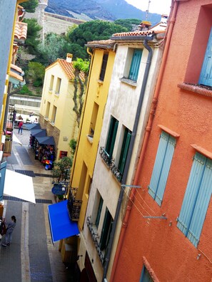 A narrow street with colorful buildings, a visible shop, and a stone wall in the background. - Collioure 20m from the beach town center appt tt comfort 4 pers.  (Collioure)