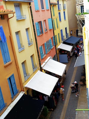 A narrow street with colorful buildings, outdoor cafes, and pedestrians.