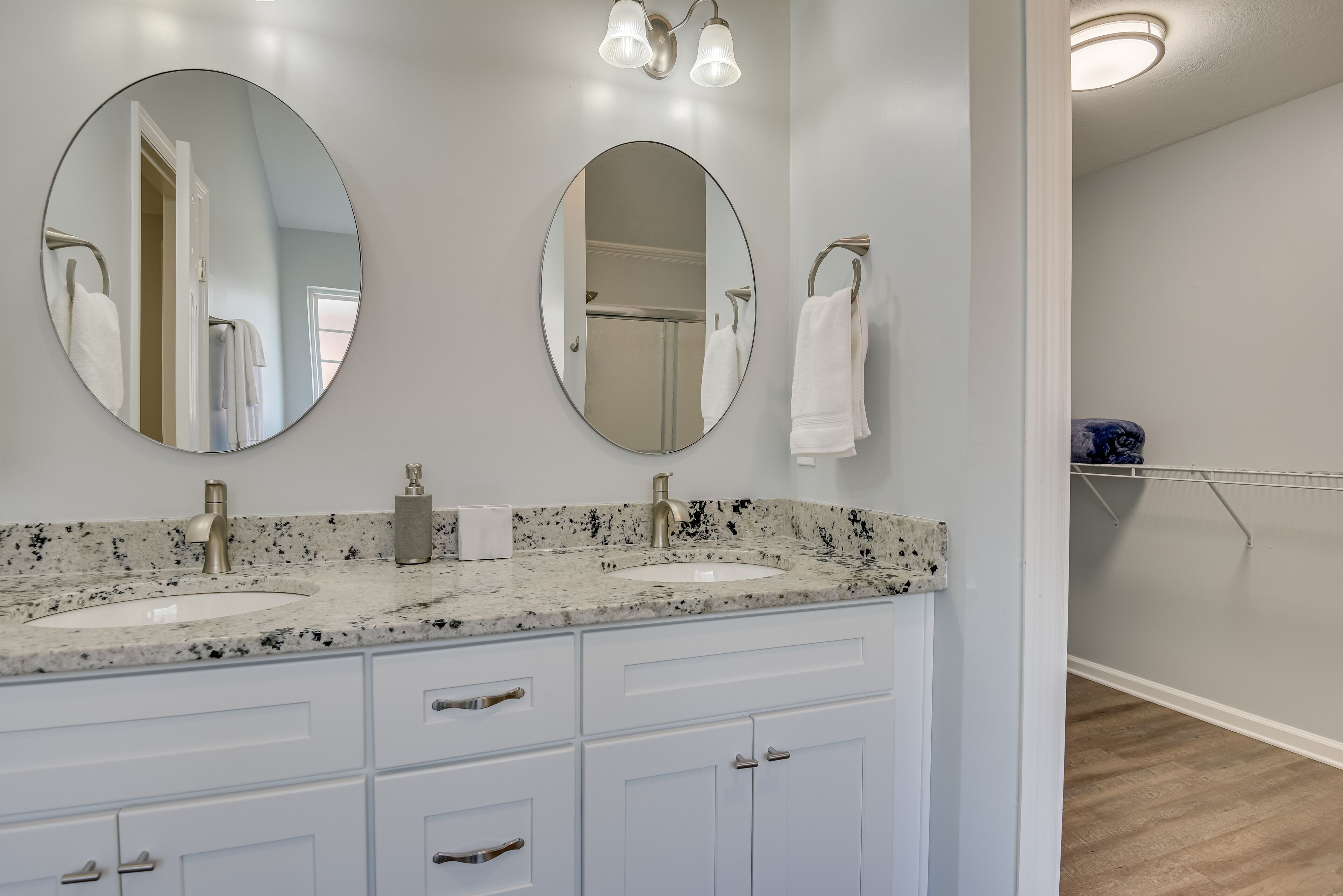A bathroom with two sinks, a mirror, and a towel rack.