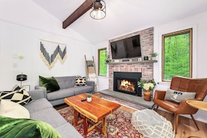 A living room with a fireplace, sofa, coffee table, and a television.