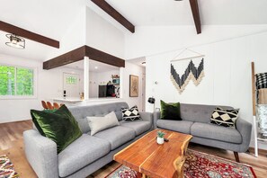 A modern living room with two grey sofas, a wooden coffee table, and a decorative wall hanging.