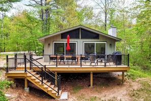 A wooden deck with outdoor furniture, a covered seating area, and a staircase leading to a covered upper level.