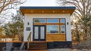 Un piccolo edificio moderno con facciata in legno, una porta nera e un cartello con su scritto "The Pine Casita".