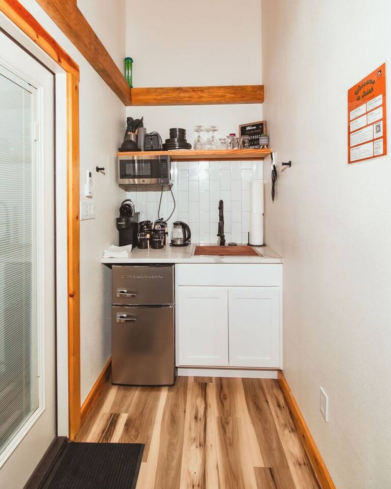 Eine kleine Küche mit Kühlschrank, Mikrowelle und Kaffeemaschine.