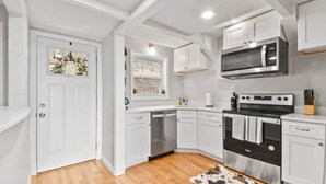 A modern kitchen with white cabinets, stainless steel appliances, and a wooden floor. - The Overlook (Winchester)