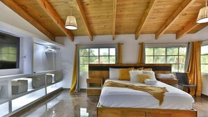 Een moderne slaapkamer met een houten plafond, een groot bed, een televisie en een raam met gordijnen.