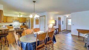 Una cocina amplia con armarios de madera, un comedor con una mesa redonda y sillas, y una sala de estar con sofá y mesa de centro.