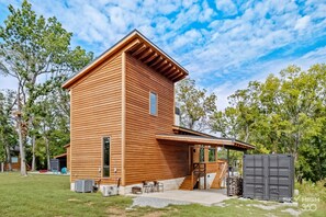 A wooden cabin with a covered patio, outdoor seating, and a large storage container. - Twin Retreat Cabin #2, Hot Tub, Near Battlefield Golf Course & Shangri La Resort (Afton)