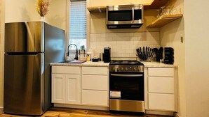 A compact kitchen with a stainless steel refrigerator, a built-in oven, and a microwave. - The Walnut Villa at Selah Place (Athens)