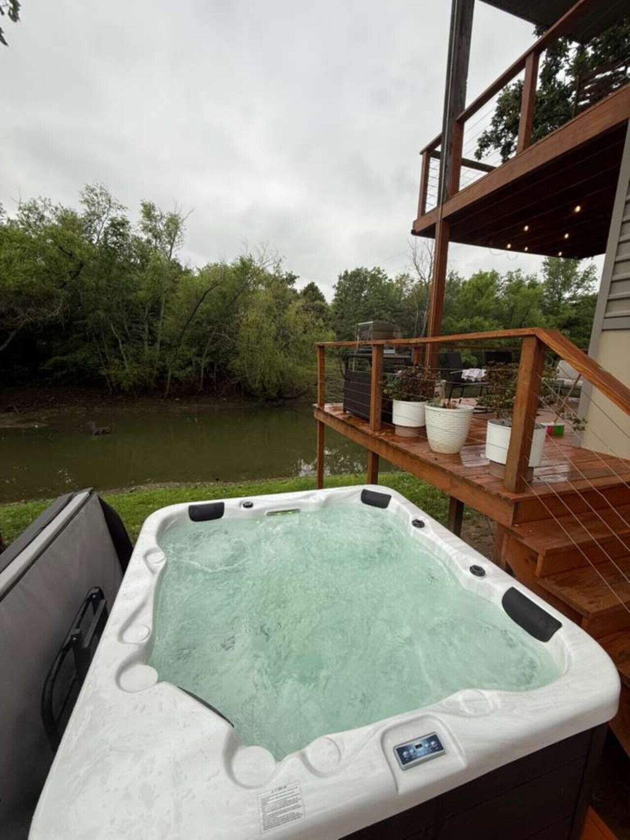 A hot tub on a deck with a view of a river and trees.