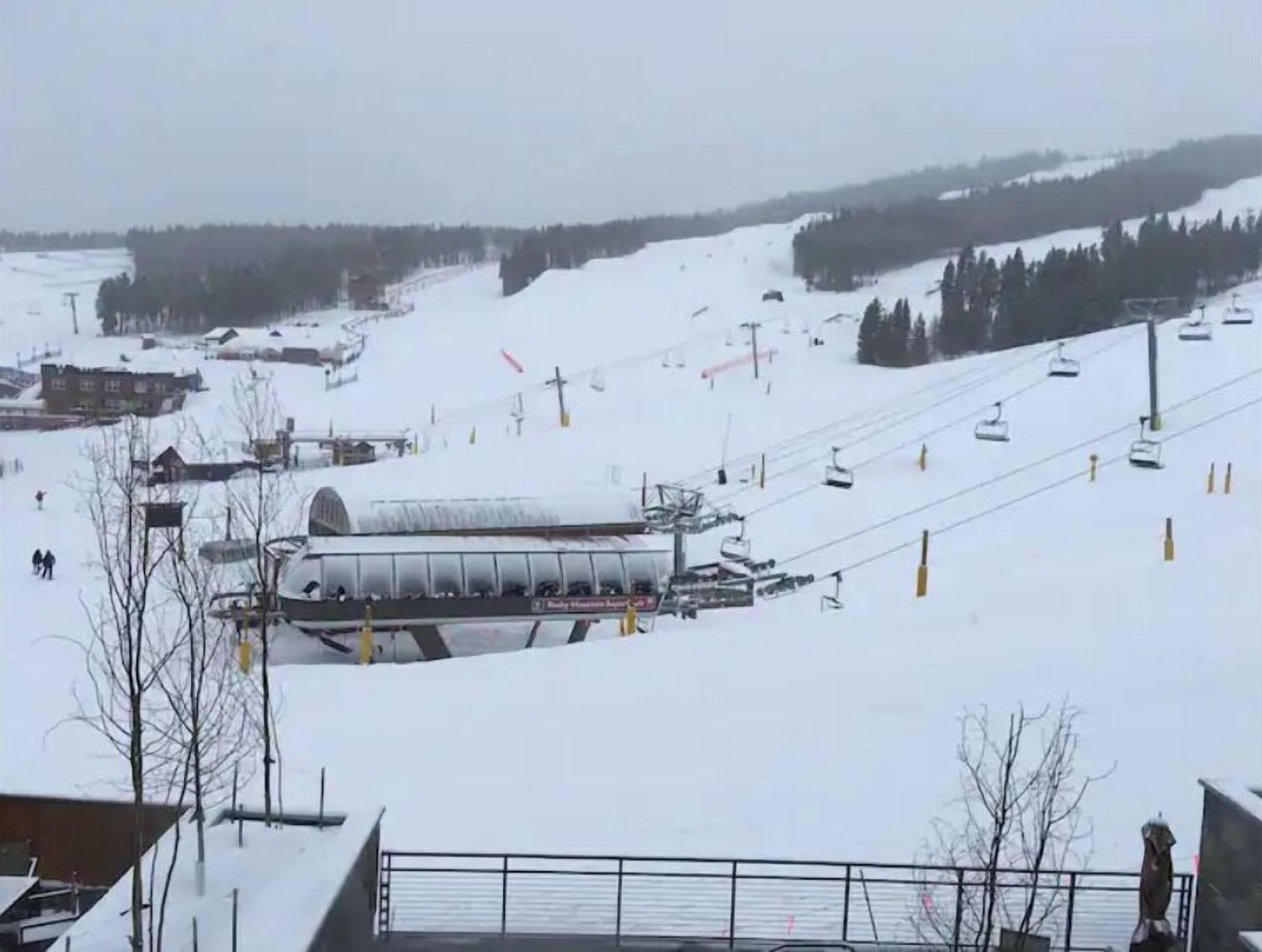 Une station de ski enneigée, dotée d'un télésiège, de bâtiments et offrant une vue dégagée sur les pistes.