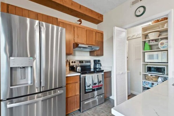 A kitchen with stainless steel appliances, wooden cabinets, and a built-in microwave shelf. - Slope Side Suite (Wintergreen Resort)