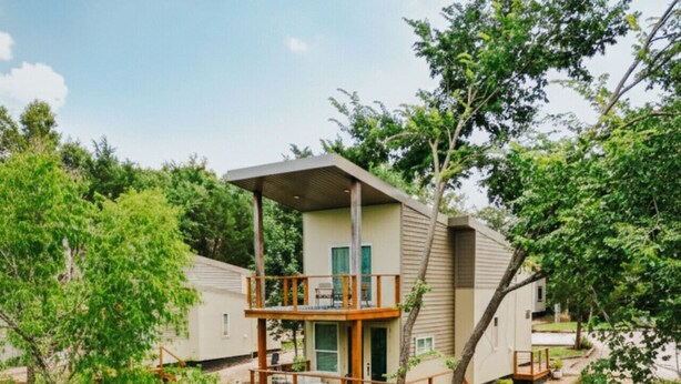 A two-story house with a deck overlooking a body of water, surrounded by trees. - Villa 1 · Waterfront Villa, spacious with 2 balcony and beds (Athens)