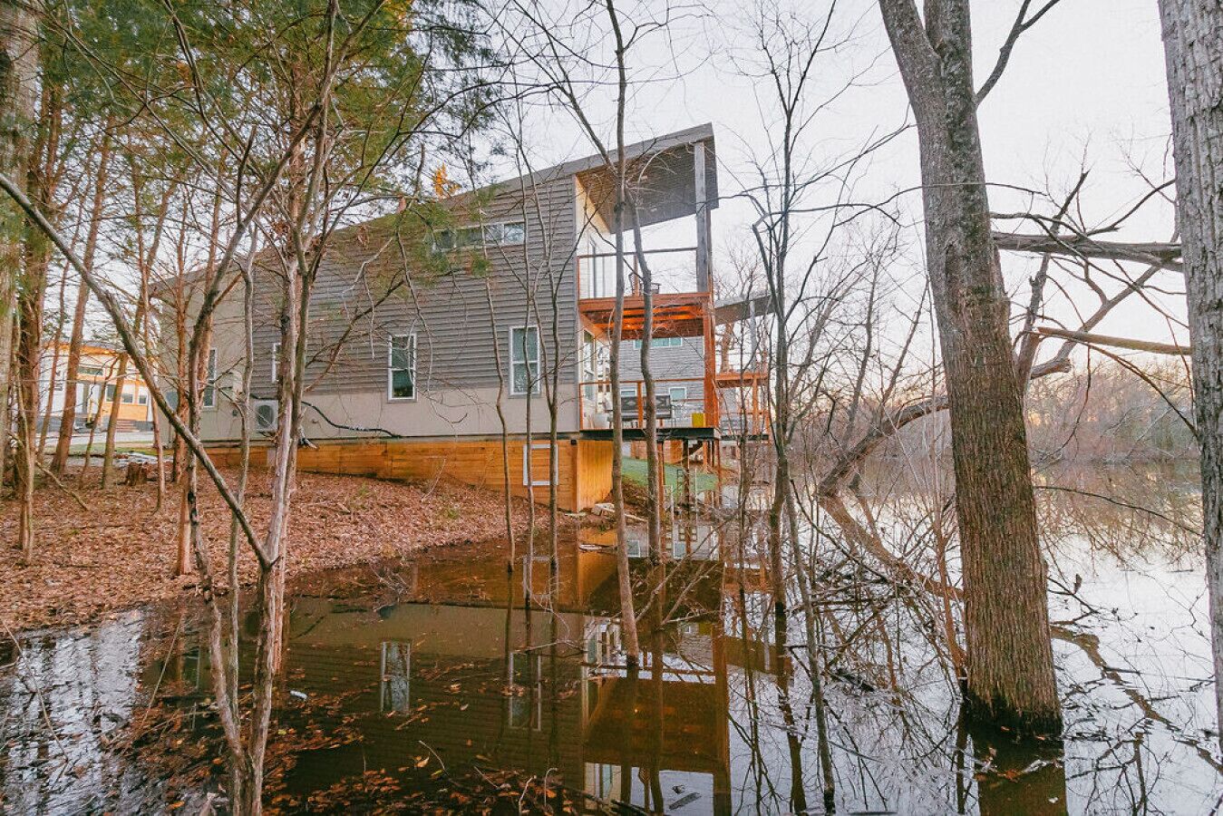 A house surrounded by trees and a body of water.