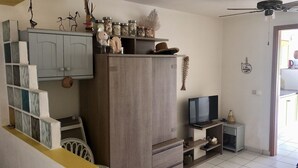 A compact living space with a grey cabinet, a television on a stand, and a ceiling fan. - Studio La Vigie 3 (Deshaies)