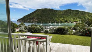 A balcony with a view of a bay with boats, a mountain, and a white railing. - Studio La Vigie 3 (Deshaies)