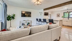 A modern living room with a sofa, dining area, and kitchen.