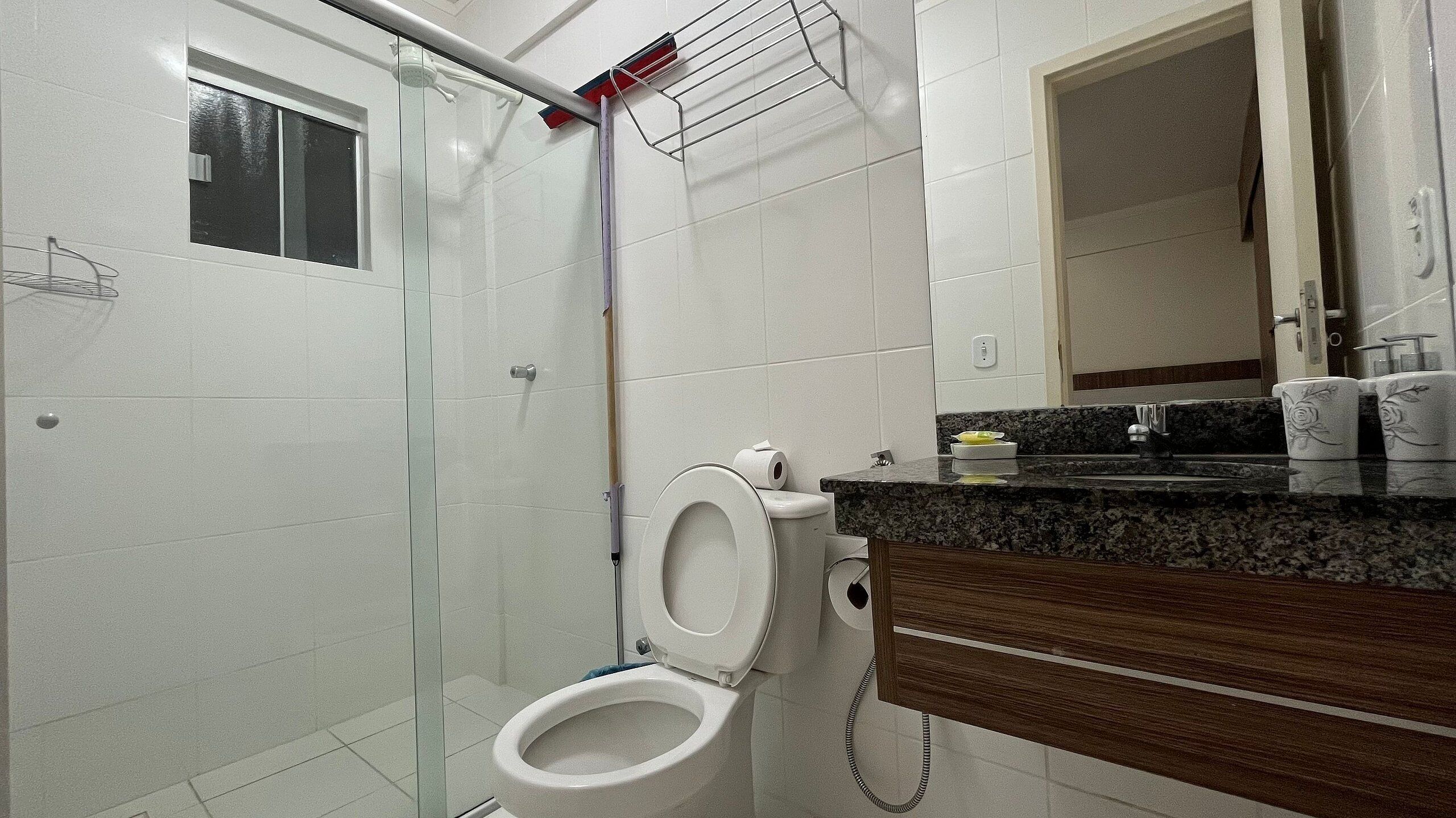Et badeværelse med toilet, brusebad, vask og spejl.