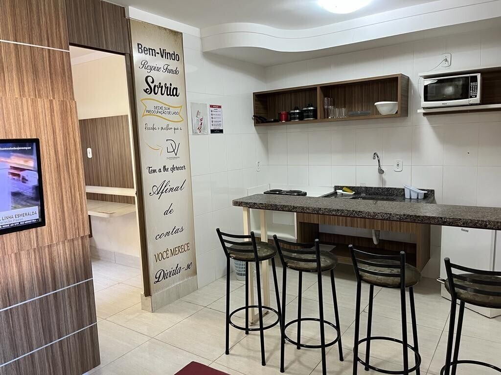 A modern kitchen with a central island, bar stools, and a microwave.