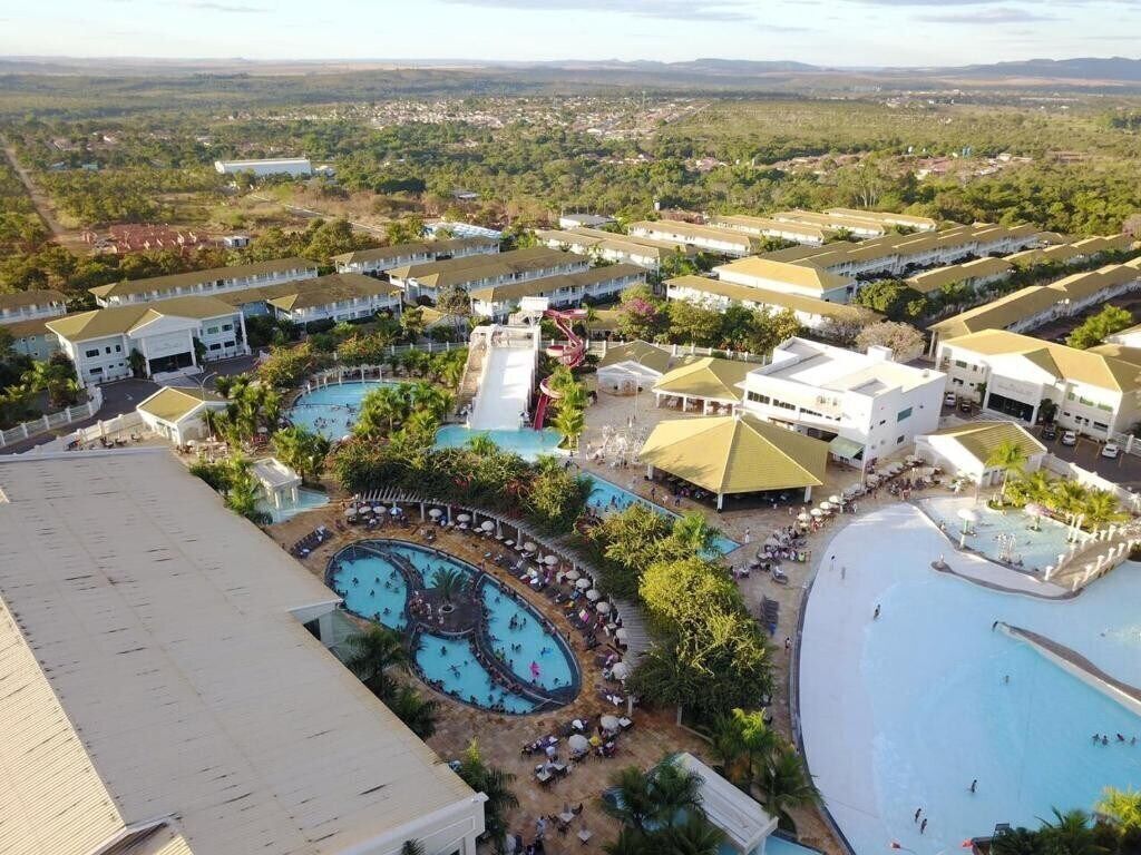 Vue aérienne d’un complexe hôtelier doté de nombreuses piscines, d’une grande piscine centrale et de divers bâtiments aux toits plats.