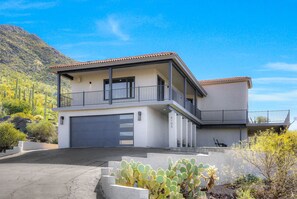Ein zweistöckiges Haus mit Garage und Balkon, vor der malerischen Bergkulisse.