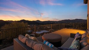 Eine Terrasse mit Gartenmöbeln und Blick auf die Berge in der Abenddämmerung.