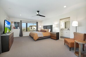 Ein modernes Hotelzimmer mit Bett, Schreibtisch, Sessel und Fernseher.