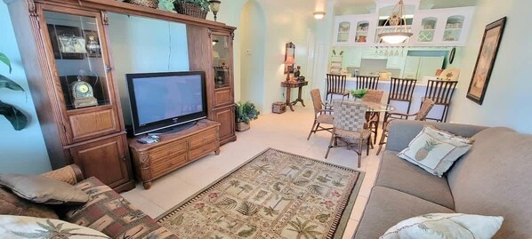 Una sala de estar con televisión, sofá y alfombra estampada.