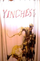 Cortina con un diseño de un hombre a caballo y la palabra 'INCHES' en letras grandes.
