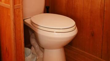A wooden bathroom with a toilet, a towel rack, and a toilet paper holder.