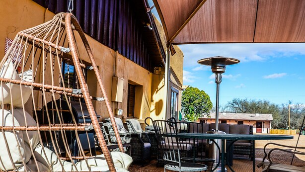 An outdoor patio area with wicker furniture, a hanging chair, and a table with chairs.