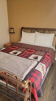 A bed with a quilt featuring animal patterns, a metal headboard, and a bedside lamp.