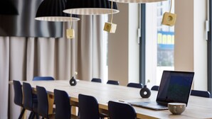 Un salón de conferencias con una larga mesa, sillas, una computadora portátil y una taza.