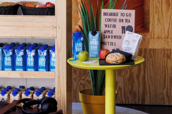 Una mesa de desayuno con un cartel, una planta, un bagel y una botella de leche.