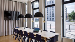 A modern meeting room with a large table, chairs, a laptop, and pendant lights. - LyvInn Hotel Frankfurt   (Frankfurt)