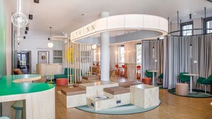 A modern interior with a curved seating area, a reception desk, and a visible name sign. - LyvInn Hotel Frankfurt   (Frankfurt)