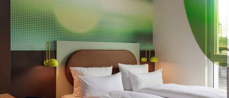 Una habitación de hotel con una cama, un escritorio con una computadora portátil y una pared verde con un diseño.