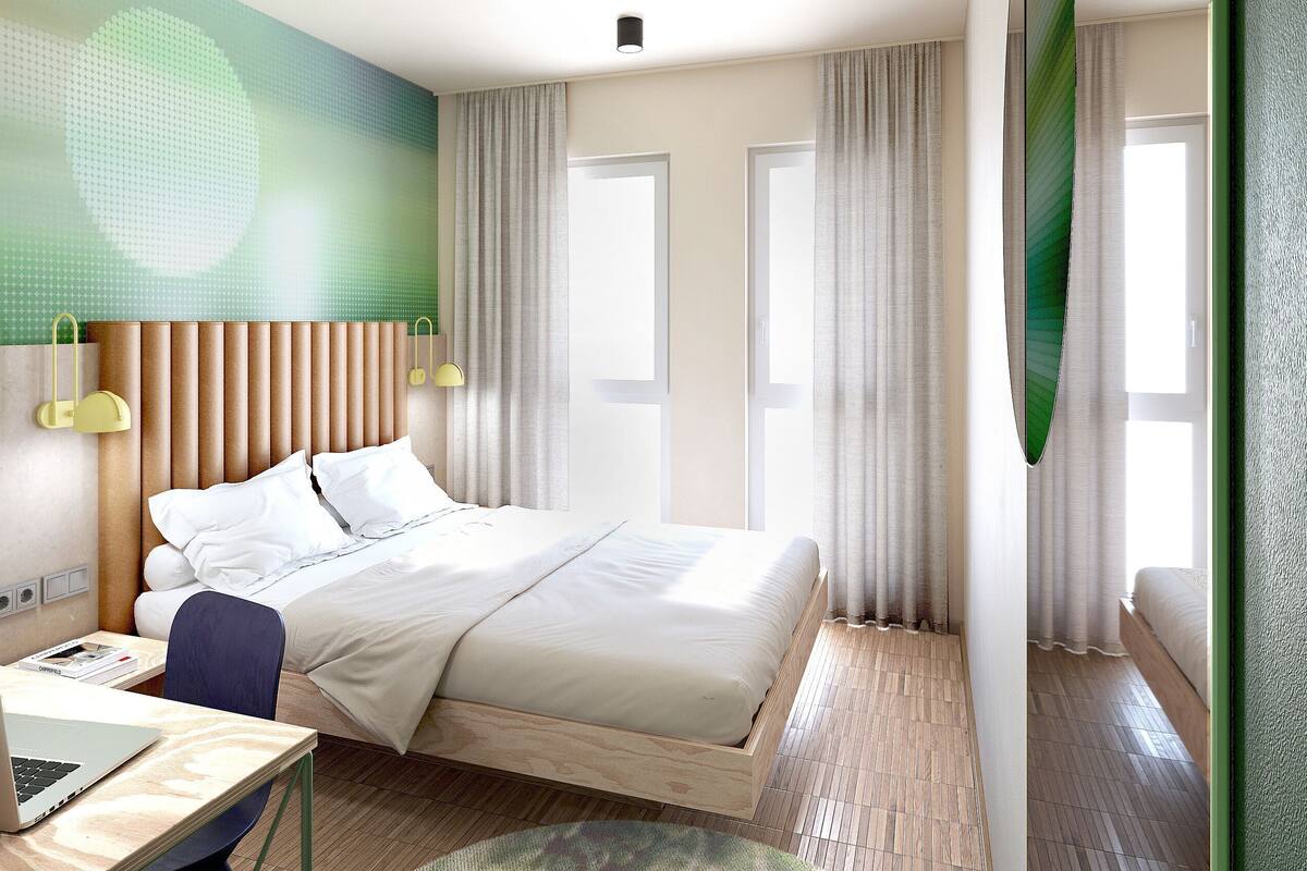 Una habitación de hotel moderna con cama, escritorio y ordenador portátil.