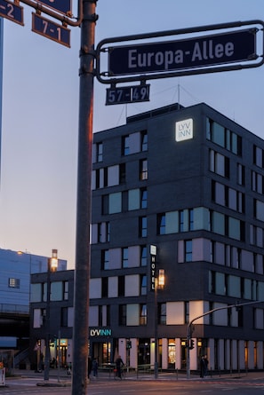 Ett hotell med flera våningar och modern design, med en tydlig skylt med texten ”LYVINN”, beläget på hörnet av Europa-Allee och 57-149.