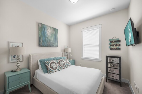 Une chambre à coucher avec un lit, des tables de chevet, une commode, un tableau et une fenêtre avec des stores.